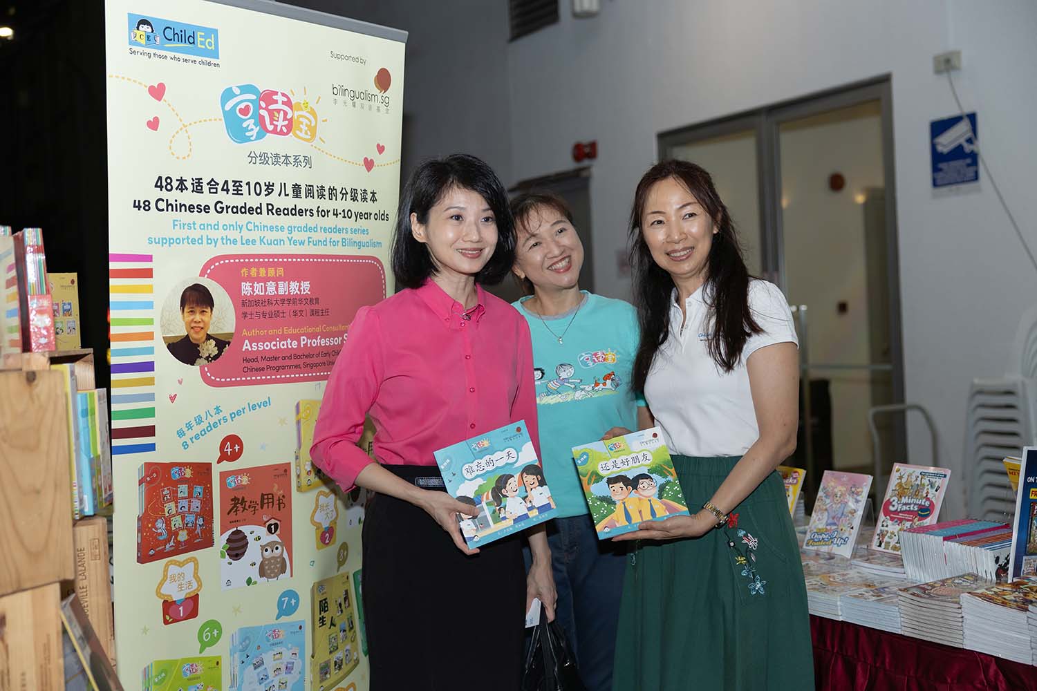 Guest Of Honour Sun Xueling and two other guests at a book booth at the Singapore Childrens Book Festival 2024, carrying some Chinese childrens books.