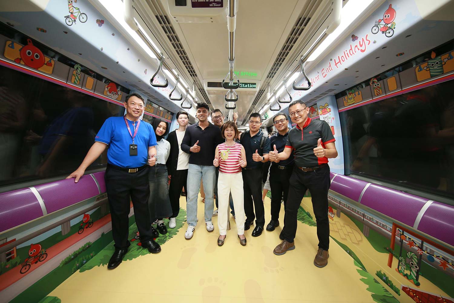Group photo of SBS Transit staff aboard the MRT interior decorated with Christmas festive illustrations.