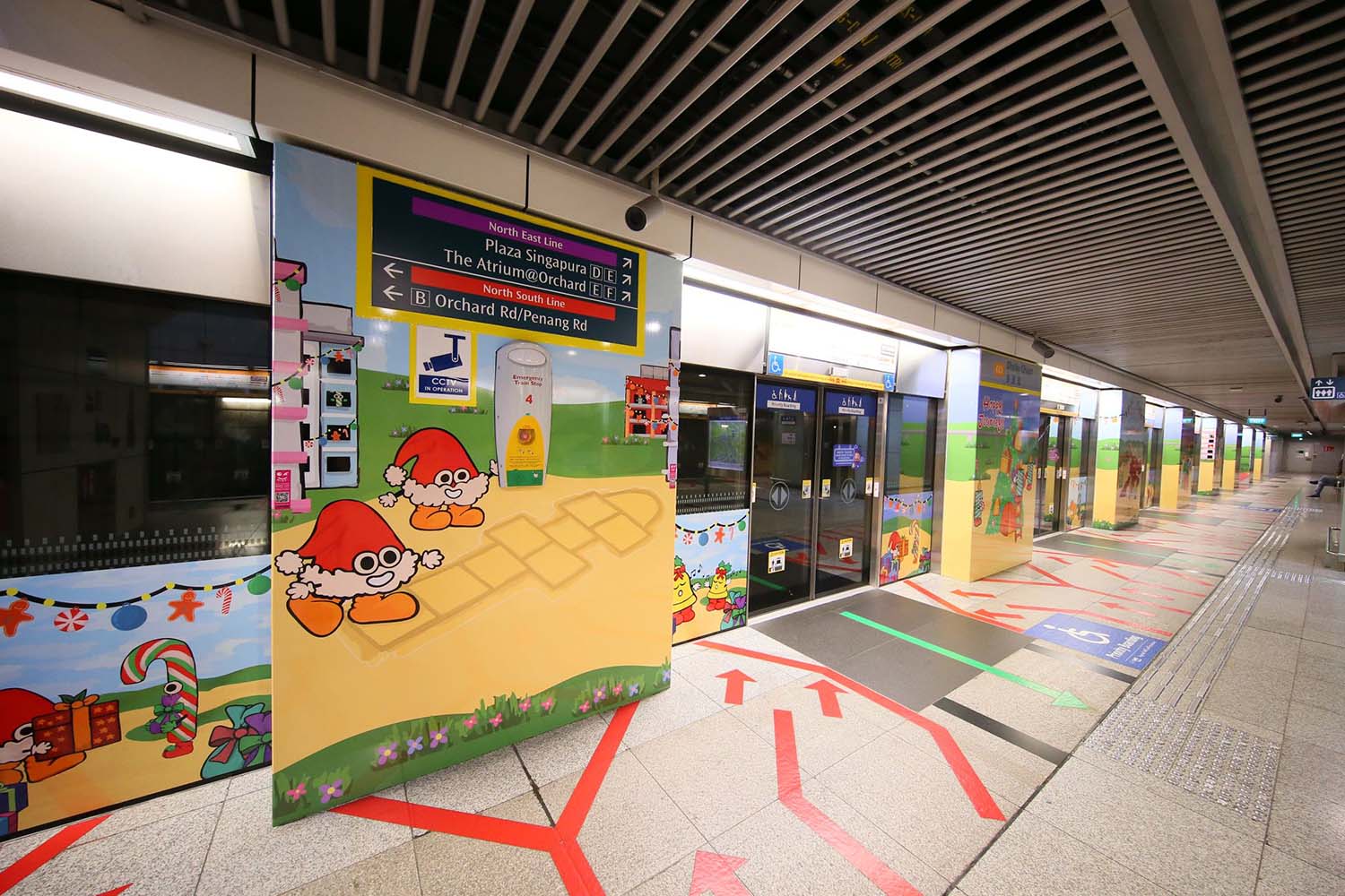 Different angled side view of various MRT entrance slide doors and panels, decorated with cartoony Christmas festive illustrations.