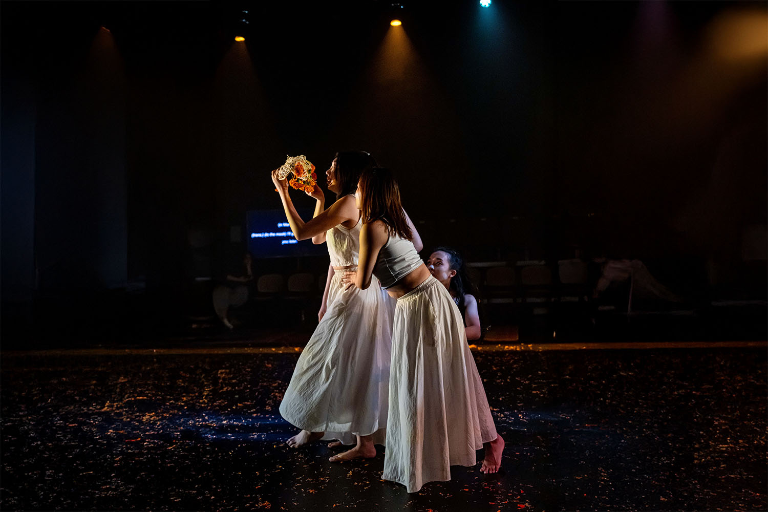 3 female performers acting in a scene on dark glittering theatre stage.