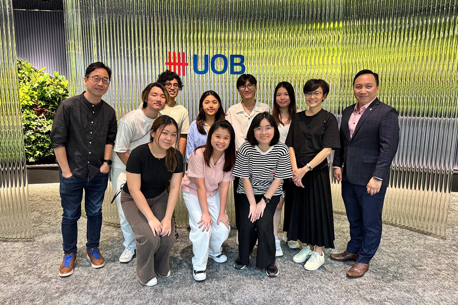 A group of diverse individuals standing together, smiling and posing in front of UOB, demonstrating the collaboration between NAFA and UOB.