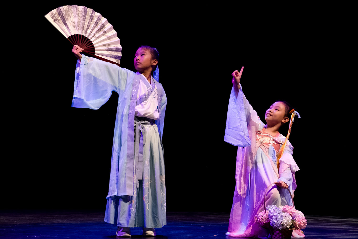 2 Junior Drama performers, both wearing traditional Chinese male and female hanfus respectively, the left one carrying folding fan.
